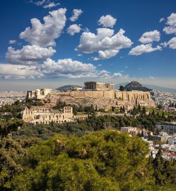 Atina, Yunanistan. Akropolis ve Parthenon tapınağı, şehrin en önemli simgesi. Antik Yunan manzarası Philopappos Tepesi 'nden kalma. Klasik Yunan harabeleriyle Atina şehir manzarası, bulutlu mavi gökyüzü.