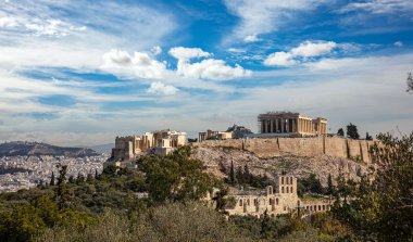 Atina, Yunanistan. Akropolis ve Parthenon tapınağı, şehrin en önemli simgesi. Antik Yunan manzarası Philopappos Tepesi 'nden kalma. Klasik Yunan harabeleriyle Atina şehir manzarası, bulutlu mavi gökyüzü.
