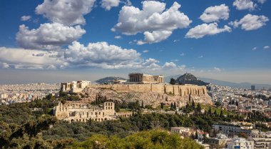 Atina, Yunanistan. Akropolis ve Parthenon tapınağı, şehrin en önemli simgesi. Antik Yunan manzarası Philopappos Tepesi 'nden kalma. Klasik Yunan harabeleriyle Atina şehir manzarası, bulutlu mavi gökyüzü.