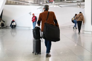 Atina Yunanistan, 3 Mart 2020. Havaalanı terminali iç kısmı. Bagajlı gezgin iş adamının arka görüntüsü. Coronavirus günleri