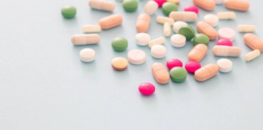 İlaç hapları, haplar ve kapsüller mavi pastel arka planda. Eczane ürünlerinin renkli varyasyonları. Tıbbi tedavi, sağlık konsepti