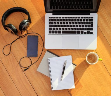 Merkez ofis, uzaktan kumanda. Bilgisayar bilgisayarı, cep telefonu, kulaklık ve yerde kahve. Telekomünikasyon, tele çalışma, evden çalışma.