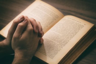 Dua, adam açık bir kitap, kutsal kitap, ahşap masa arkaplanı verir. İnanç, din ve maneviyat kavramı