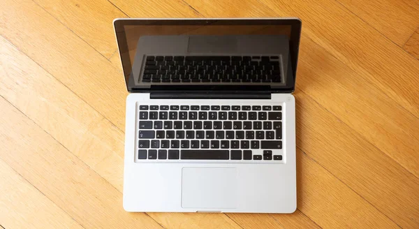 Laptop open on wooden floor, Working from home concept, high angle view