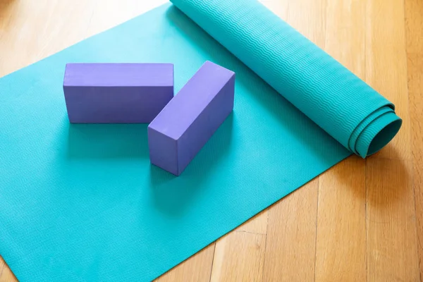 Yoga mat and exercise bricks on wooden floor. Pilates, yoga class, training at home and healthy lifestuyle concept
