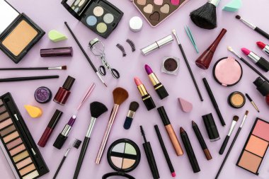 Makyaj malzemesi yatıyordu. Ruj ve tırnak cilası, göz farı ve allık, fırçalar ve kalemler, pastel mor arka plana karşı