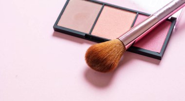 Allık tozu paleti, pastel renkler ve pembe arka plana sürtünme, yakın görüş. Makyaj malzemeleri, güzellik salonu, kozmetik konsepti.