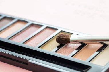 Göz farı paleti, pastel kahverengi renkler ve pembe arkaplan üzerinde fırça, yakın görüş. Makyaj malzemeleri, güzellik salonu, kozmetik konsepti.