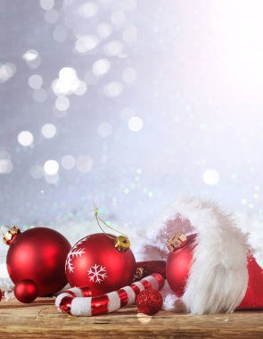 Noel hediyeleri. Xmas süsleri ve hediyeler ahşap bir masanın üzerindeki Noel Baba şapkasından, karlı bokeh arka planı, dikey, kopyalama alanı