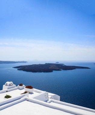 Santorini Adası, Yunanistan, Caldera 'da deniz manzaralı beyaz teras. Mavi denize karşı geleneksel mimari ve temiz gökyüzü arkaplanı, dikey fotoğraf