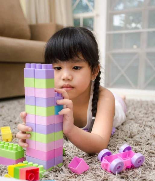 Щаслива дівчинка, яка грає з будівельними іграшковими блоками, будує вежу. Діти грають. Дитячі та іграшки — стокове фото