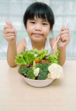 Kavramı çok küçük sevimli tatlı gülümseyen kız yiyor taze salata / sağlıklı yeme
