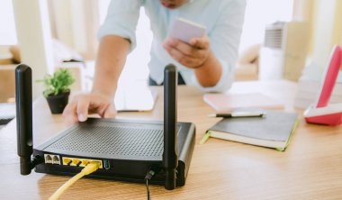 bir kablosuz yönlendirici ve oturma odası, ev kat üzerinde akıllı telefon kullanan bir adam closeup