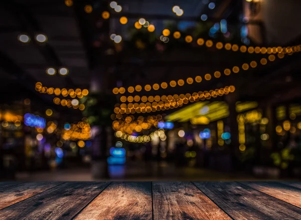 Image of wooden table in front of abstract blurred restaurant lights background — Stock Photo, Image