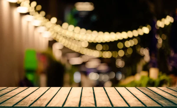 Image of wooden table in front of abstract blurred restaurant lights background — Stock Photo, Image