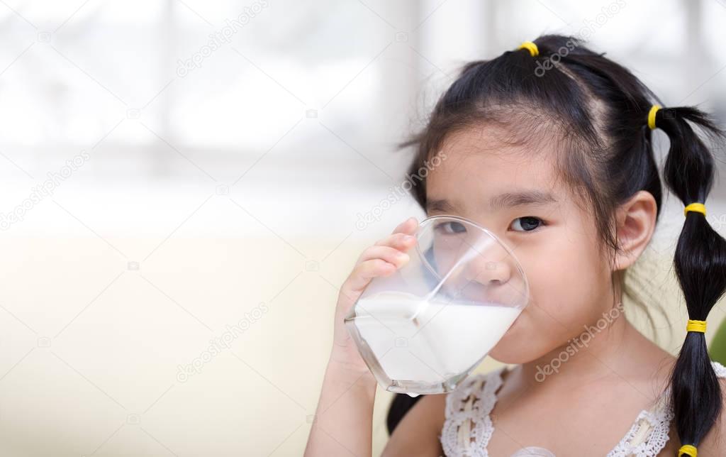 asian girl drinks a glass of milk on living room background