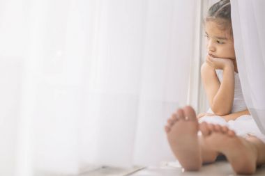 Evde pencere yakınındaki depresif küçük kız