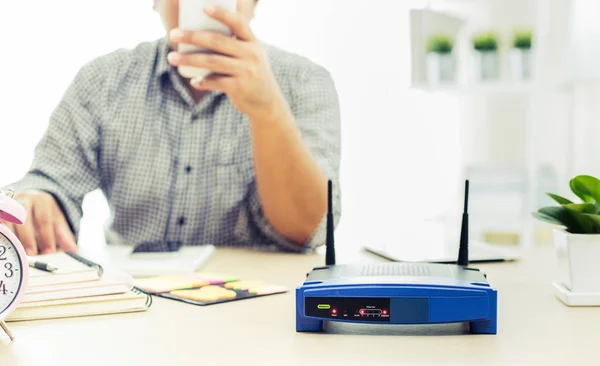 Närbild av en trådlös router och en man med smartphone på livin — Stockfoto