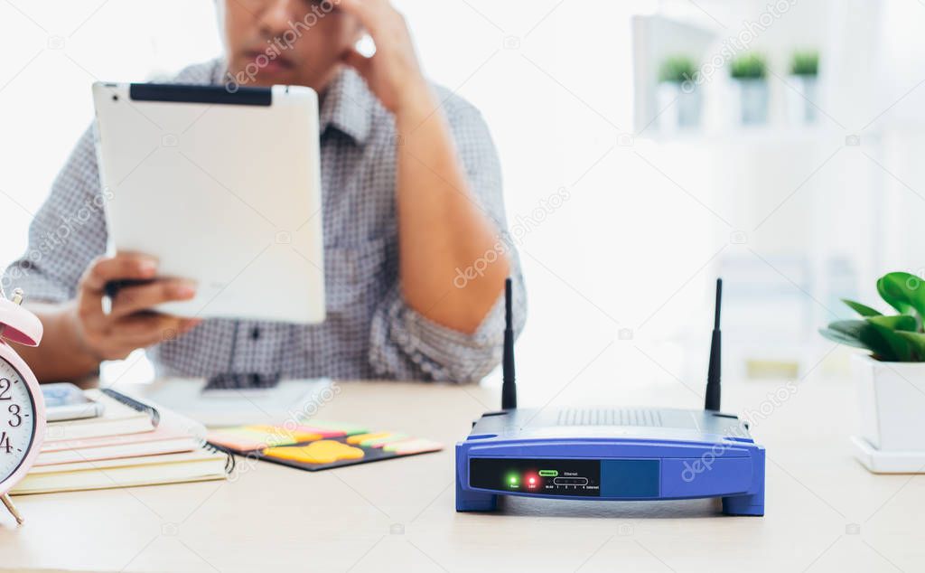closeup of a wireless router and a man using smartphone on livin