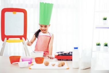 Asyalı çocuk hamur hazırlama ve pişirme ile eğleniyor fırında kurabiye mutfakta