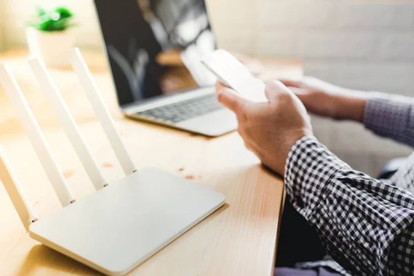 Närbild av en trådlös router och en man med smartphone på vardagsrum — Stockfoto