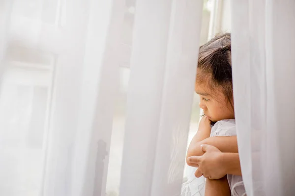Красивая маленькая девочка смотрит в окно — стоковое фото