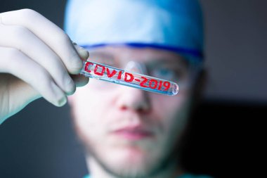 COVID-2019 Coronavirus virüsü olan tıbbi test tüpü bir doktorun elinde.