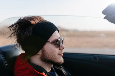 Erkek Cabriolet araba sürücüsü güneşli bir günde güneş gözlüğü takıyor..