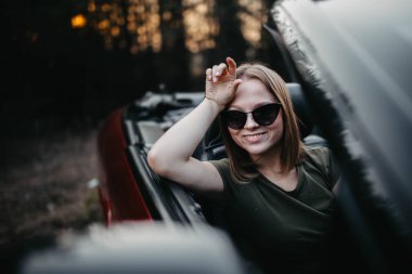 Gün batımında genç kadın Cabriolet araba şoförü. Yolculuktayken