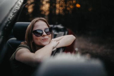 Gün batımında genç kadın Cabriolet araba şoförü. Yolculuktayken