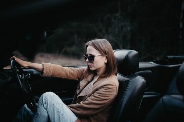 Gün batımında genç kadın Cabriolet araba şoförü. Yolculuktayken