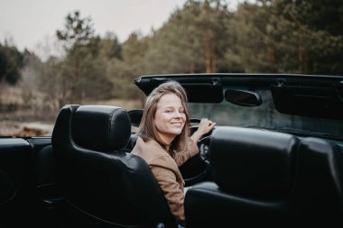 Gün batımında genç kadın Cabriolet araba şoförü. Yolculuktayken.