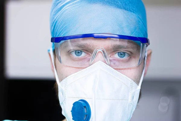 surgeon in antiviral mask and protective medical glasses and uniform. Professional uniform of a doctor.