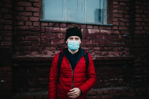 young man in a medical mask in a city during a pandemic.