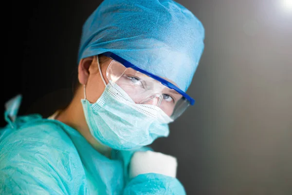 Female doctor in uniform, glasses and mask works concentrated in the hospital. portrait of a surgeon