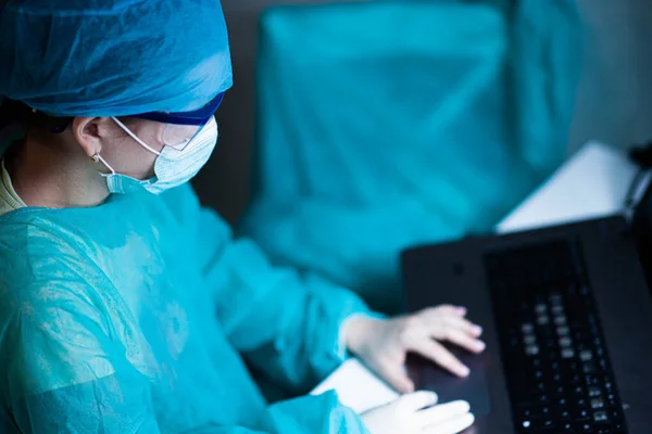 Female doctor in uniform, glasses and mask works concentrated in the hospital. portrait of a surgeon