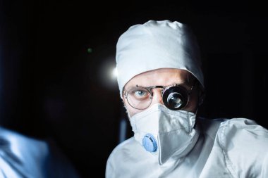 Üniformalı ve gözlüklü bilim adamı cam büyüteçle virüsün maddesini kapsülde inceliyor. laboratuvar testleri.