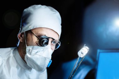 Üniformalı ve gözlüklü bilim adamı cam büyüteçle virüsün maddesini kapsülde inceliyor. laboratuvar testleri.