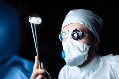 Üniformalı ve gözlüklü bilim adamı cam büyüteçle virüsün maddesini kapsülde inceliyor. laboratuvar testleri.