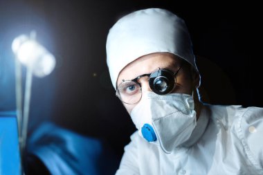 Üniformalı ve gözlüklü bilim adamı cam büyüteçle virüsün maddesini kapsülde inceliyor. laboratuvar testleri.