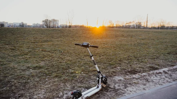 夏に緑の芝生の上で白い電動スクーター 二輪都市環境輸送の概念 — ストック写真