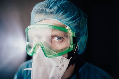 Koruyucu üniformalı bir adam ve epidemiyoloji uzmanı gözlüklü bir adam geceleri hastanede ekrana bakıyor.