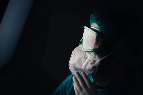 man in a protective uniform and glasses of epidemiologist doctor looking at screen in hospital at night