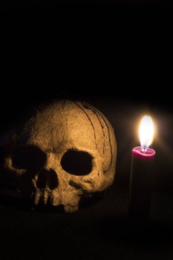 Siyah Magicskull ve koyu renk arka plan üzerinde eski kitap üzerine de mum