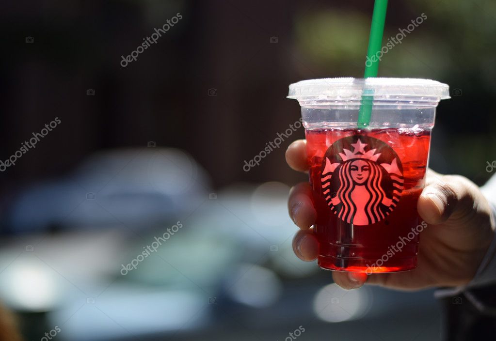NEW YORK, NY - SEPTEMBER 25th, 2016: Man holding Starbucks plastic cup on city blurred background