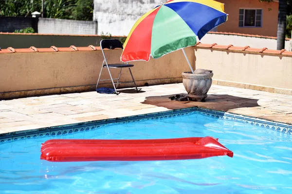 Red inflatable pool raft in pool on sunny day