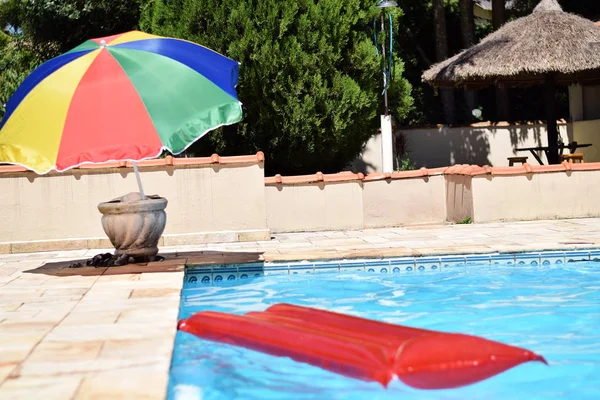 Red inflatable pool raft in pool on sunny day