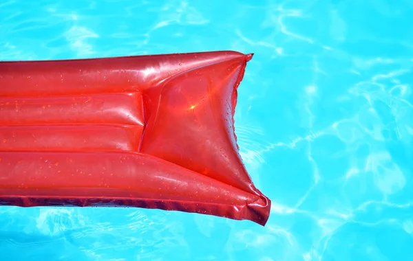 Red inflatable pool raft in pool on sunny day