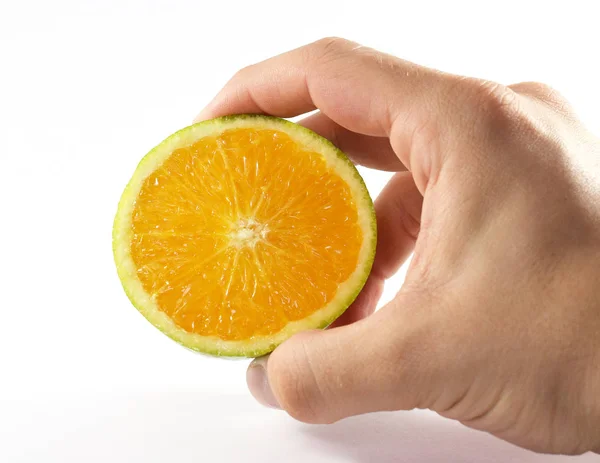 Mano masculina sosteniendo la mitad de una fruta naranja cortada — Foto de Stock