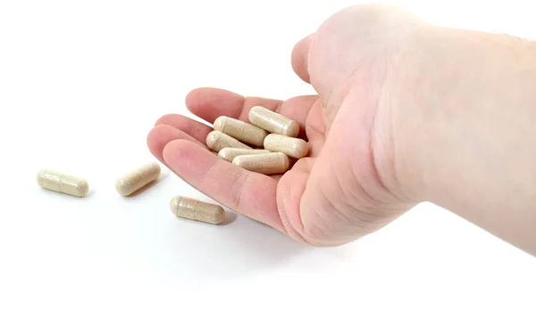 Mano masculina sosteniendo cápsulas de píldora beige con medicamento en ellos — Foto de Stock